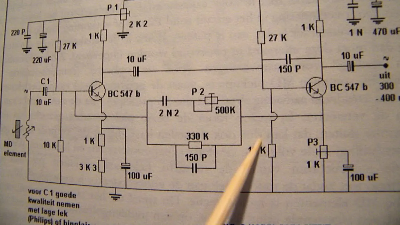 A printed circuit schematic with a pencil resting on it, transistors and capacitors labelled by hand